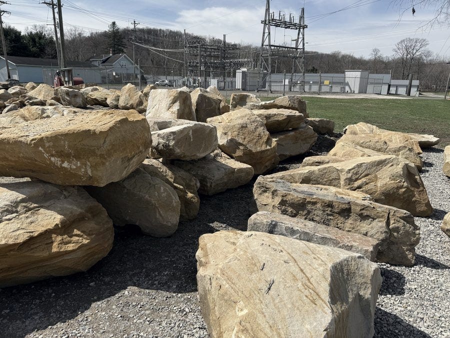 Sandstone boulders and stackable stones stacked in long rows at the supply yard.