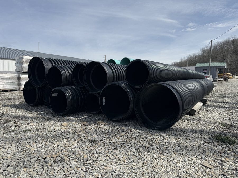 Large-diameter black corrugated culvert pipe stacked in the supply yard.