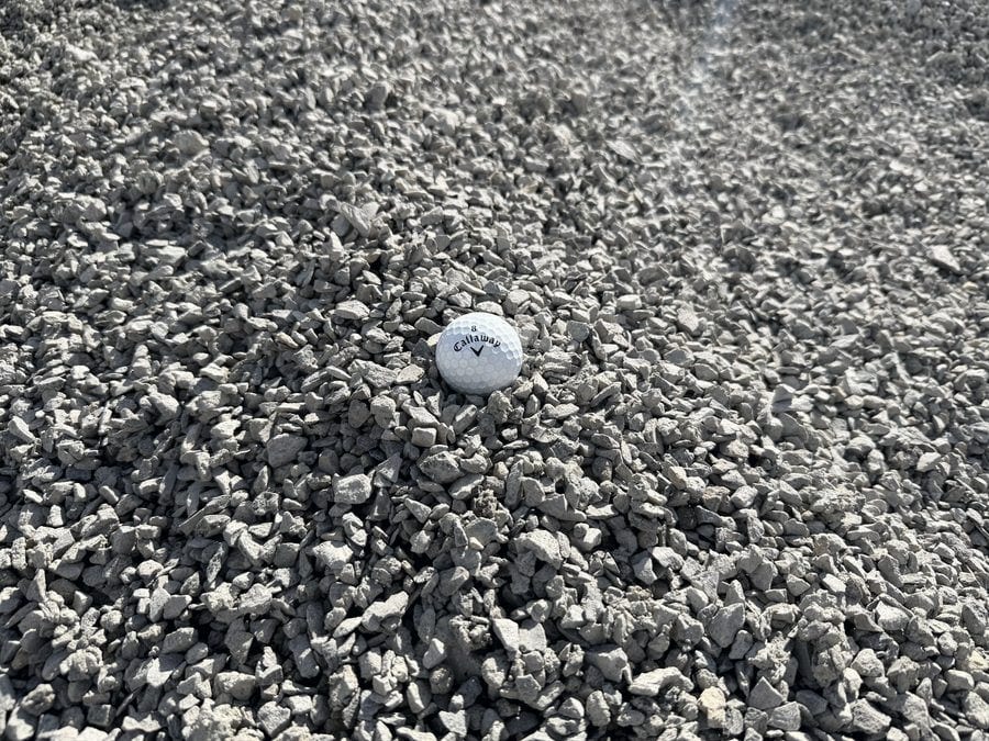 Small angular gray limestone chips, well under the width of the golf ball resting on the pile.