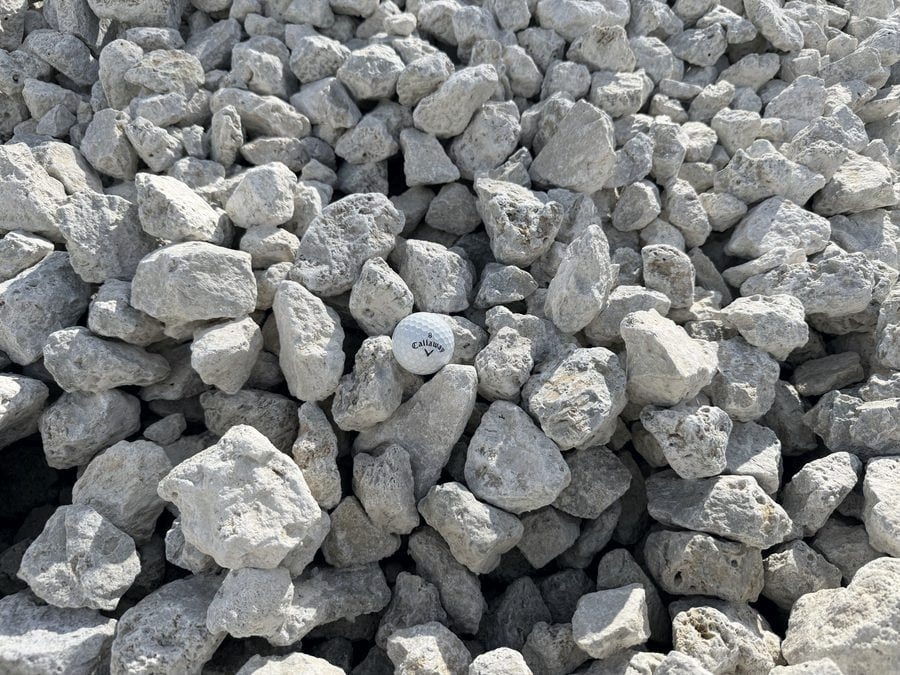 Chunky white limestone, most pieces larger than the golf ball set among them.