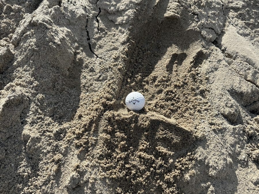 A pile of fine pale sand, shown with a golf ball for scale.
