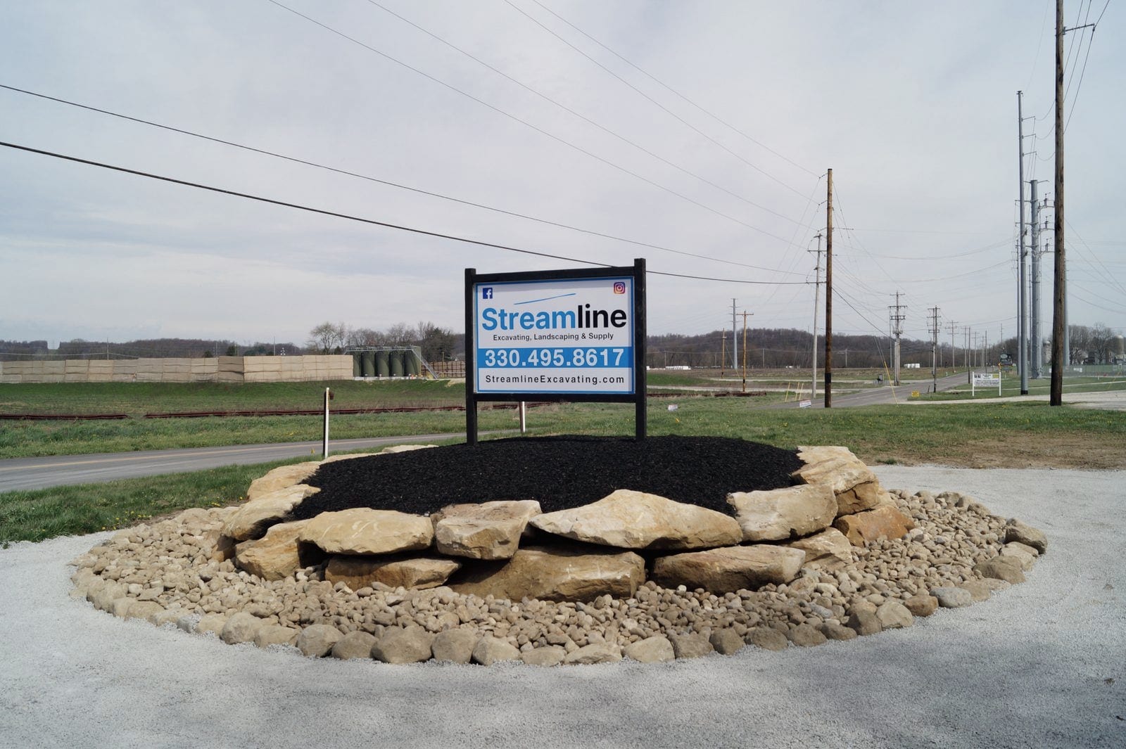 The Streamline roadside sign at the supply yard, set in a mulched bed ringed with sandstone boulders and stone.